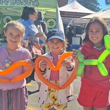 Happy child holding a green balloon animal at a community event