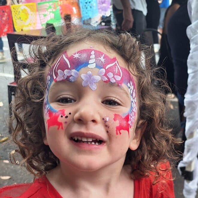 Smiling child with colourful unicorn face painting
