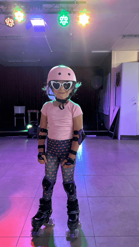 Child wearing skates and safety gear at an indoor session